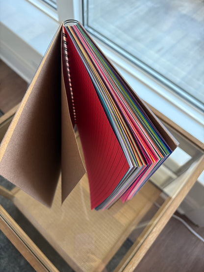 Stack of colorful paper journal on a reflective surface