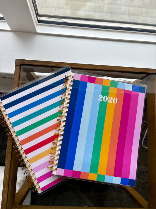 Colorful 2026 planner with striped design on a wooden stand.